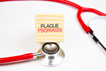 PLAQUE PSORIASIS text on a wooden cube with a stethoscope. Psoriasis medical concept.