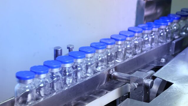 pharmaceutical industry - vaccine drug glass vial ampoules in a medicine factory creative view of small vials collected for manufacturing small glass injection moving in a pharma equipment machinery	