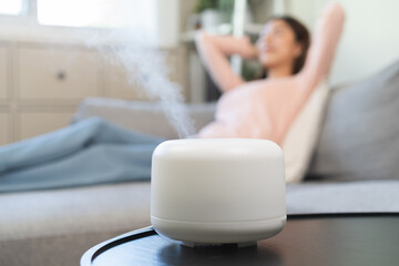 Modern air humidifier during relax or rest, happy blurred asian young woman, girl enjoying...