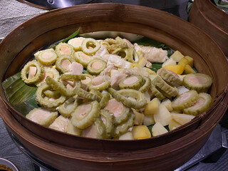 Siomay, traditional snack from Indonesia, in traditional wooden bamboo pan. With steamed tofu, bitter melon slices and potato cuts