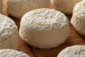 Group of fresh made French Crottin de chevre on wicker surface close up 