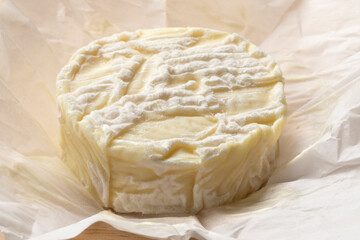 Single French Pico goat cheese unpacked on paper close up