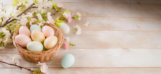 Easter eggs in a basket on a wooden table with spring flowers, cherry branch. Copy place. Top view. . Easter card and banner. Generative AI - 797917747