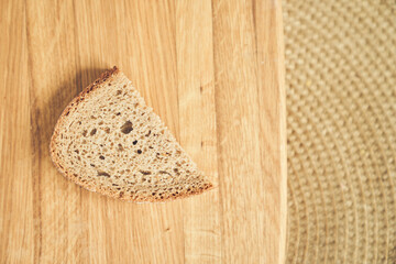 Top view of one slice of dark gluten-free rye bread against a wooden board with space to copy. High...