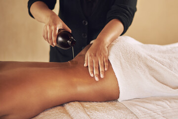 Woman, back and massage with oil at spa to relax or wellness with luxury or body therapy services for skincare. Hand, therapist and holistic healing with liquid for self care or peace on vacation