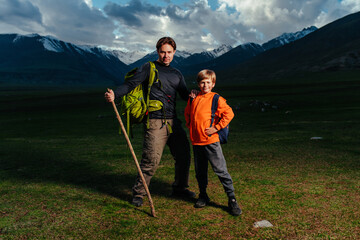 Man hiker with his son standing in the mountains at dusk