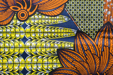 top view of orange ankara fabric, flatlay of nigerian wax cloth with designs, spread out orange ankara material - obrazy, fototapety, plakaty
