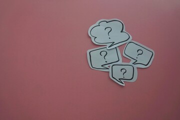top view of of black question mark on white speech bubble on a pink background.