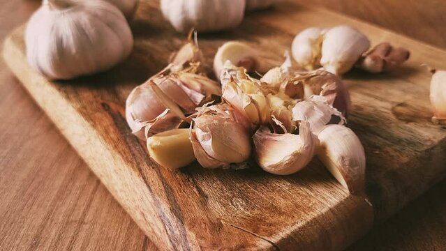 chopping garlic bulbs with a knife, on a chopping board, wooden table, knife, rustic style, mobile video, without people,