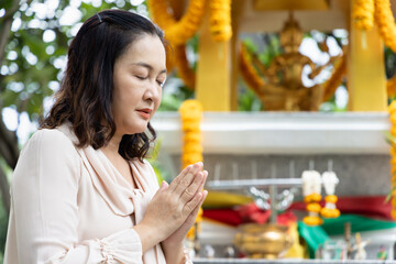 Relaxed middle aged woman praying at Brahman God Shrine, religious service