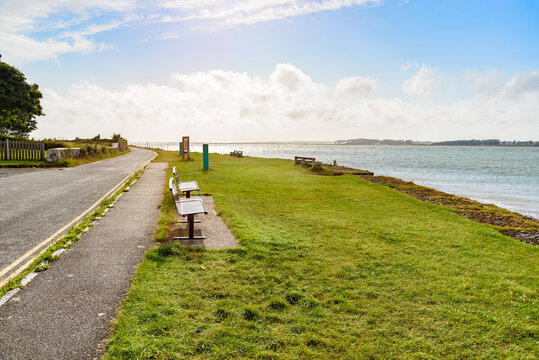 Deserted small park with beches on grass along a coast road at sunset in summer