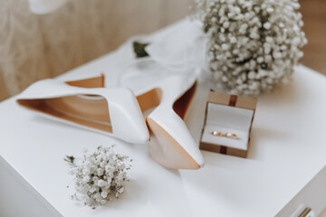 A pair of white shoes and a white flower arrangement sit on a table