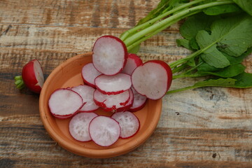 freshly harvested red radish cut in slices on a clay dish.