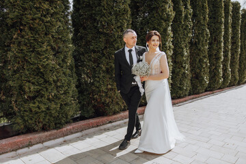 A man and a woman are walking down a sidewalk, the man is wearing a suit and tie