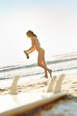 Woman, bikini and walking on beach sand for summer with surfing, holiday peace and watersports. Surfer girl, ocean and swimwear with surfboard, sunny and nature for vacation adventure in Australia
