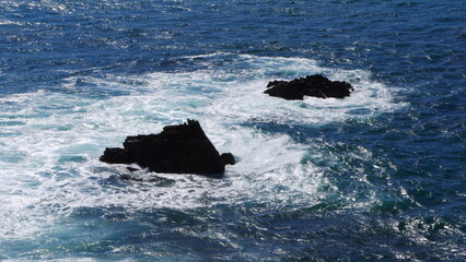 Gros plan de grands rochers dépassant l'eau de mer, dans une zone côtière de la Bretagne, vagues...
