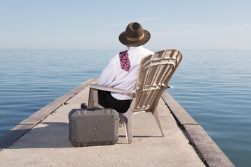 an unidentified  business man in a white shirt and red tie sitting on a chair on a dock with a...