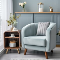 b'Blue velvet armchair with a gray cushion and a wooden side table with a vase of flowers and a cup of coffee on it.'