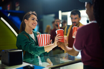 Young happy woman buying drinks and snacks in movie theater.