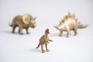 Golden dinosaur figurines on a white background.