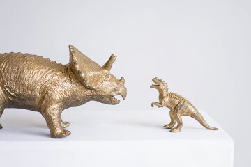 Golden dinosaur figurines on a white background.