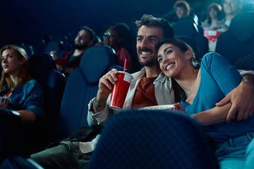 Happy couple enjoying in film projection in cinema.