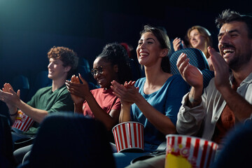 Happy spectators applauding after movie projection in cinema.