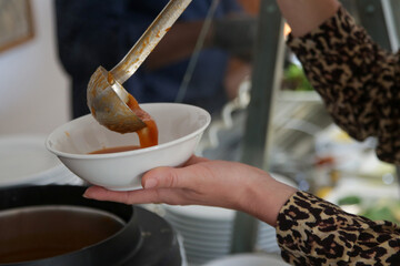Woman taking soup from a buffet line