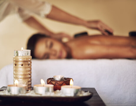 Candles, hot stones and wax light at a spa for lomi lomi massage, healing or luxury treatment therapy. Health, aromatherapy and wellness products for calm, zen or peaceful atmosphere at natural salon