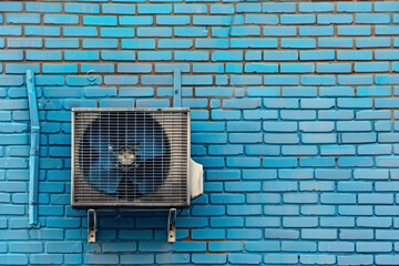 An outdoor air conditioning unit attached to a modern building with windows and a facade.

