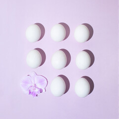 Creative layout made of eggs and orchid flower on pastel purple background. Flat lay. Easter concept.