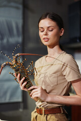 Woman holding a lobster in front of a stove preparing a delicious seafood dish