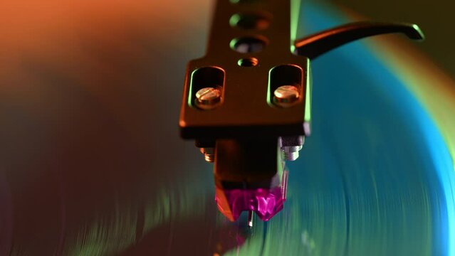Classic stylus needle traces grooves of vinyl record. Neon light. Music nostalgia. Retro vibes, vintage aesthetics, analog sound.