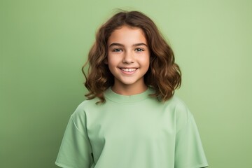 Fototapeta premium A young girl with long brown hair is smiling and wearing a green shirt