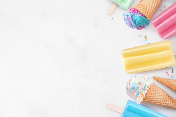Collection of colorful pastel ice cream cones and popsicle summer frozen desserts. Above view side border on a white marble background. Copy space.