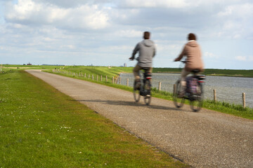 Blur. National Park in Holland. Landscape in spring on a sunny day. Cyclists on dam Netherlands, Zeeland, Oosterschelde.