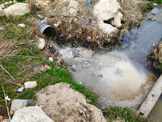 Obraz premium Environmental pollution. A sewage pipe drains toxic wastewater into a river, causing environmental pollution and ecological damage