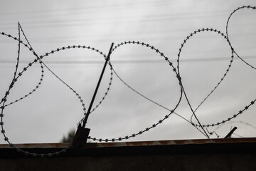 Barbed wire stretched along the brick walls. Barbed wire fence.