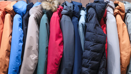 A row of jackets of various colors and styles. The jackets are hanging on a rack. The jackets are...
