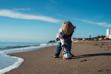 Toddler on vacation. Boy plays with a toy car on the seashore. boy 3-yers old playing on the seashore with a truck. carefree childhood. baby playing at sea