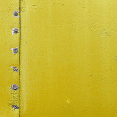 Vintage metallic board. Yellow color template frame, old metal door surface with screws.