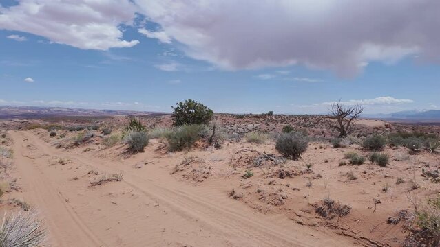 Panning view of sandy dirt road through the Escalante desert in Utah during Spring.