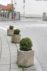 MSZANA DOLNA, POLAND - APRIL 23, 2024: Flowerpots against parking cars on the pedestrian sidewalk...