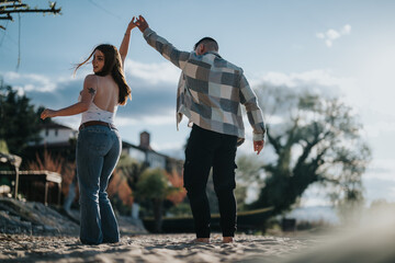 A happy couple enjoys a spontaneous dance on a sandy beach, celebrating their vacation with joy and...