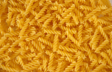 spiral pasta sprinkled on the background. background of yellow spiral pasta.