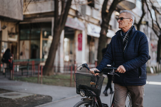 A mature man with a bicycle stands on an urban sidewalk, reflecting a relaxed lifestyle and active aging in a city environment.