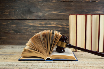 Law concept - Open law book with a wooden judges gavel on table in a courtroom or law enforcement...