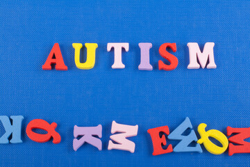 AUTISM word on blue background composed from colorful abc alphabet block wooden letters, copy space for ad text. Learning english concept. - 798134902