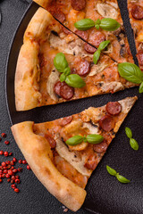 Delicious pizza with sausage, cheese, tomatoes, salt, spices and herbs
