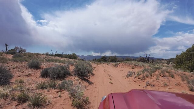 Driving through the desert in Escalate on sandy road as storm clouds roll through the sky.